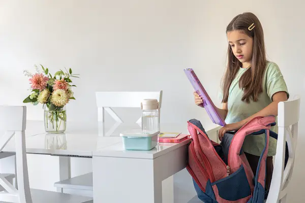 niña escolar organizando sus útiles escolares en casa